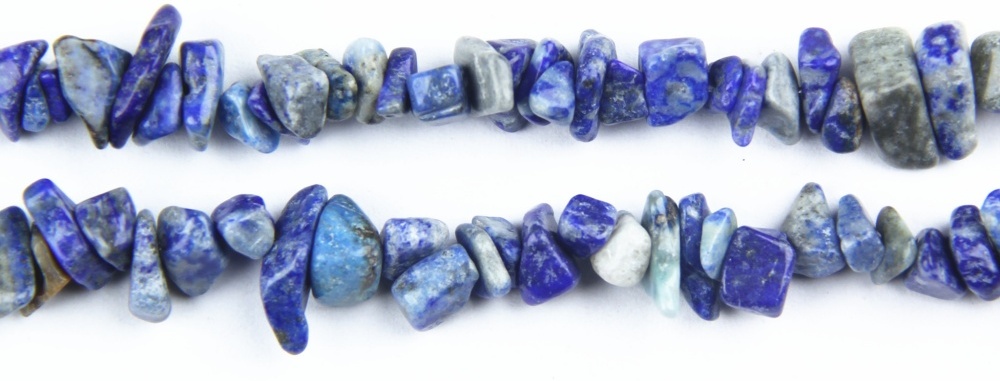 Close-up of vibrant cobalt blue gemstone chips - natural lapis lazuli chip beads showing rich royal blue color and golden pyrite inclusions