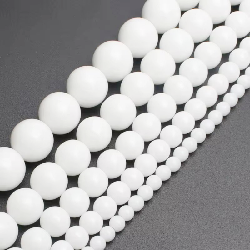 Close-up of White Ceramic Beads (4-12mm), round porcelain beads on a 40cm strand, ideal for jewelry making projects.